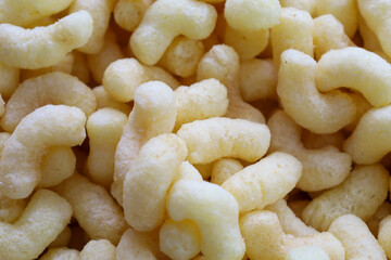 Fresh corn puffs in close-up create an appetizing texture, demonstrating their lightness and airiness. This golden snack is ideal for backgrounds and promotional materials.