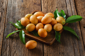Fresh Yellow Mangoes Surrounded by Green Leaves on a Rustic Wooden Background