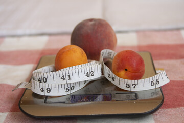 peach and apricots with measuring tape on kitchen scale promoting healthy eating