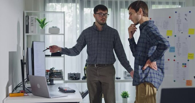 Team adult male engineer collaborate on robotic hand project using AI code solutions machine learning at tech workspace. Artificial intelligence interface, collaboration support prototype development.