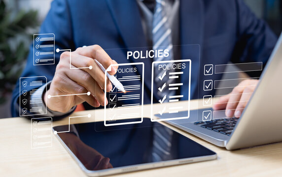 Businessman reviewing company policy and compliance checklist requirements professionally on laptop using digital online document on virtual screen. Holographic interface technology.