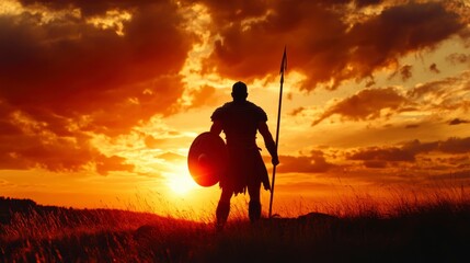 Silhouette of a warrior with shield and spear at sunset.