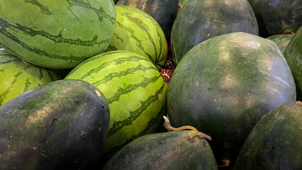 Pile of watermelons, Watermelons sold in fruit shops in the market, watermelons with minimal light with high photo quality, as a background for health promotion or tropical fruit education