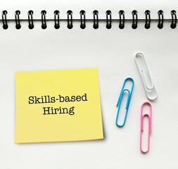 Stick note on notebook with text written Skills-based Hiring - refers to practice of employers...