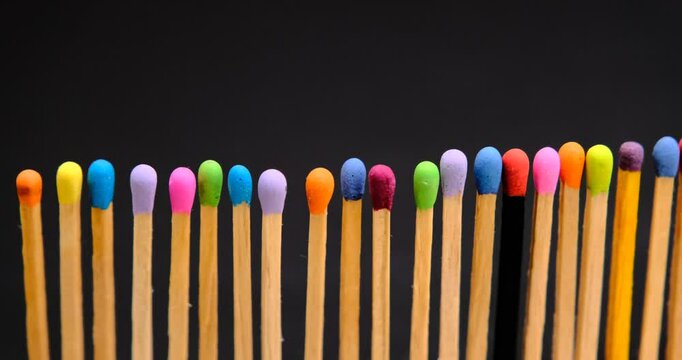 multicolored match sticks in rotation on a rotating table with black background, close up view