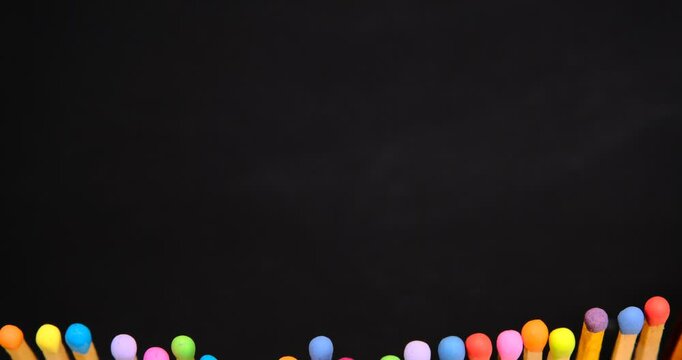 multicolored match sticks in rotation on a rotating table with black background, close up view