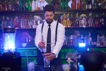 Bartender preparing cocktail in stylish bar with colorful backlight