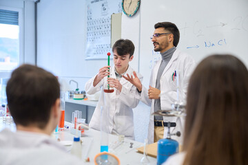 Chemistry teacher helping student during experiment in laboratory