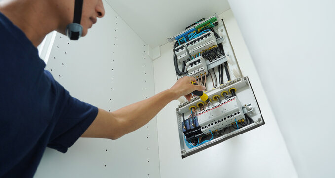 Electrician working checking a switchboard with fuses