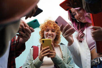 Students using smartphones standing together in a circle