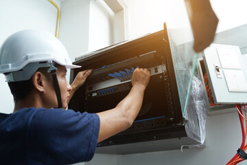A maintenance technician works in a server room with a fiber optic hub