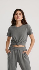 Full length of confident Argentinian girl in a knotted tshirt and athletic shorts standing while tilting her head playfully on plain white background
