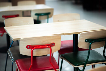 Modern wooden and metal chairs and tables in a contemporary interior setting, highlighting minimalistic design and colorful accents, suitable for cafes, coworking spaces, or dining areas.