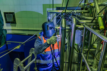 Male worker wearing protective clothing of repair pipe stainless argon welding industrial
