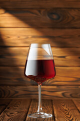 glass red wine basks in dramatic beam of light, sitting elegantly on rustic wooden table