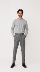 Full length of confident Saudi man in a plain crewneck shirt and slacks standing with his arms behind his waist and smiling gently on plain white background