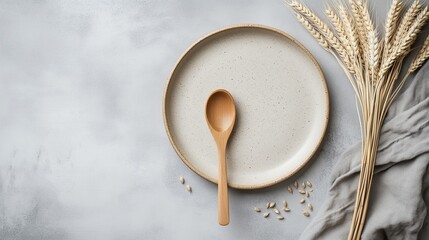 Beige plate with wooden spoon and wheat on gray background, flat lay

