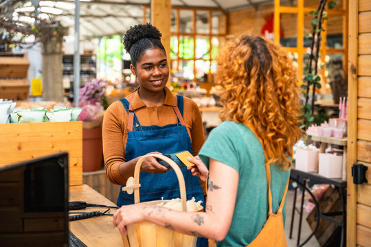 Smiling cashier accepting contactless payment from customer in flower shop