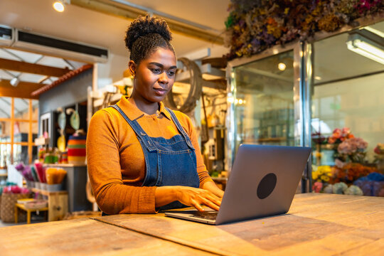 Florist managing online orders in flower shop using laptop