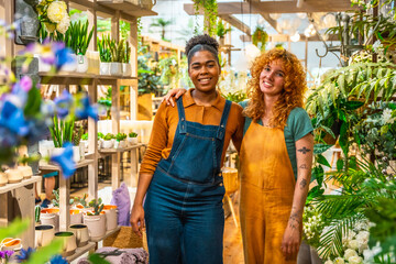 Two young florists smiling and posing together in flower shop