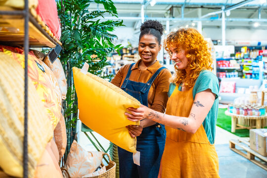 Sales assistants holding yellow pillow in home furnishing store