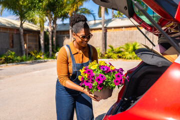 Gardener loading flower pots into car trunk on sunny day