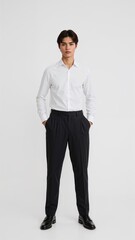 Full length of confident Japanese boy in a white dress shirt and slacks standing with hands in pockets on plain white background