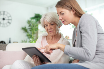 grandmother learning how to use tablet with granddaughter