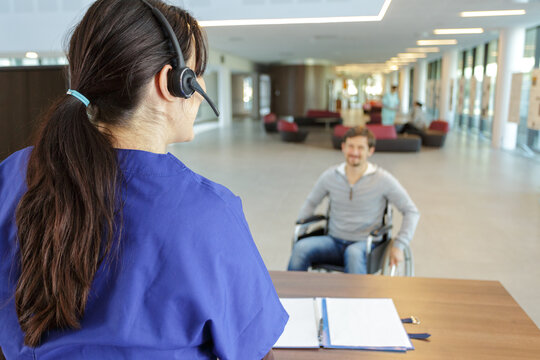 man in wheelchair in reception area - Powered by Adobe
