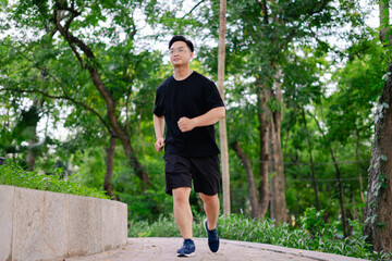 Man jogging on a pathway surrounded by trees during daylight in a peaceful park setting