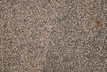 Rough asphalt surface covered with scattered sand particles