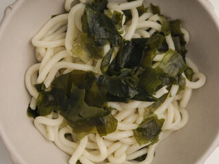 Soba noodles cooked in broth with seaweed, isolated on white background
