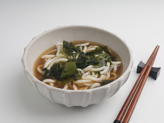 Soba noodles cooked in broth with seaweed, isolated on white background