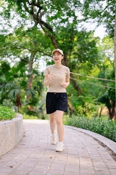 Young woman jogs along a winding path in a lush urban park on a sunny day, enjoying her exercise routine