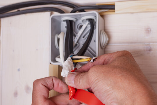 Electrician carefully insulates exposed wires in open junction box, ensuring safety during residential electrical installation work.