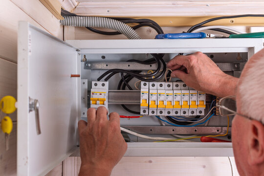 Experienced technician adjusts circuit breaker inside modern electrical panel, focusing on safe operation and proper wiring installation.