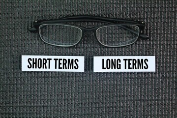 Colored glasses and paper with the words short terms and long terms. business concept. Short-term...