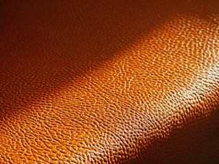 Diagonal ray of light falling on orange leather surface