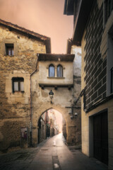 Historic stone archway and narrow street in Medina de Pomar, Burgos, Spain, at sunrise. Medieval architecture and charming old town atmosphere