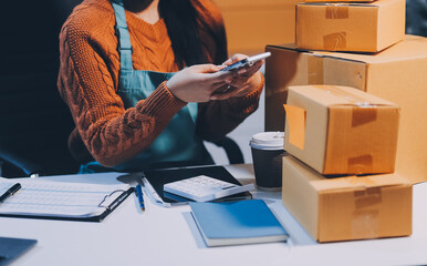 Startup SME small business entrepreneur of freelance Asian woman wearing apron using laptop and box...