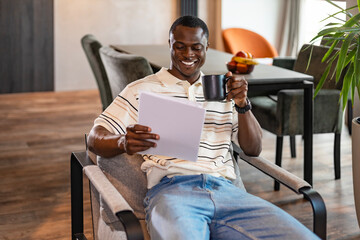 A serious young african entrepreneur accountant, financier, analyst, auditor sits at home at the table. He types on a laptop.