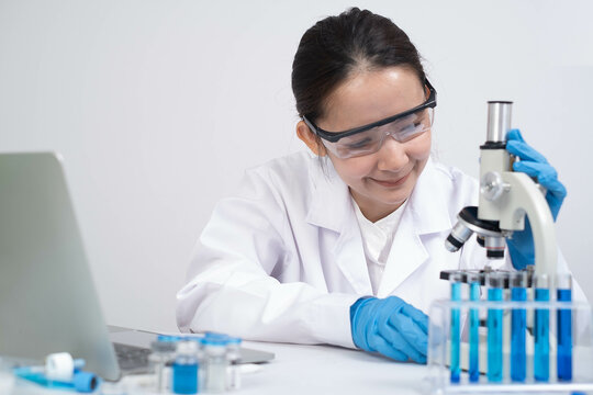 A focused scientist examines samples under a microscope in a lab, showcasing expertise in research and technology with safety gear and equipment.