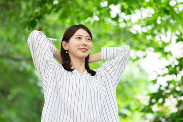 新緑の中に立つ笑顔の女性