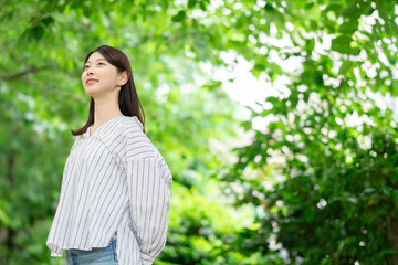 新緑の中に立つ笑顔の女性
