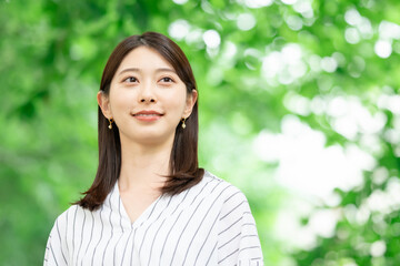 新緑の中に立つ笑顔の女性