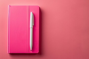 Premium Quality Visual of Closed Pink Notebook with a White Pen on a Pink Surface