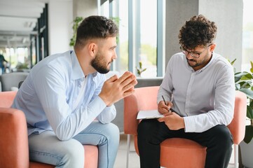 Psychologist taking notes while listening to patient talking about problems