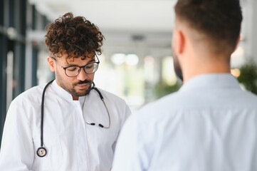 Fototapeta premium Arab doctor listening to patient in hospital corridor