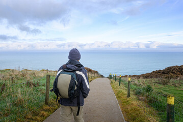 Tourist walking on Tunnel Beach track in winter. Dunedin. South Island.
