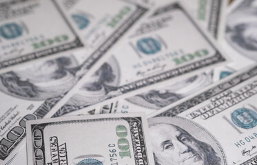 A close-up view of scattered hundred-dollar bills, showcasing the intricate details and textures of U.S. currency.